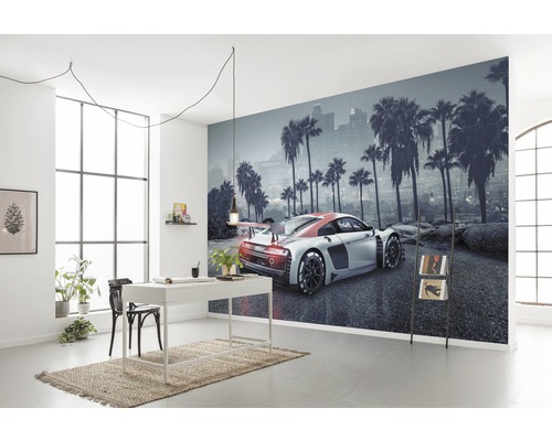 Wohnraum mit Fototapete, die ein Auto vor einer Skyline mit Palmen zeigt, dazu Schreibtisch, Stuhl und Deko.