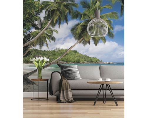Wohnraum mit Fototapete, die einen tropischen Strand mit Palmen und blauem Himmel zeigt