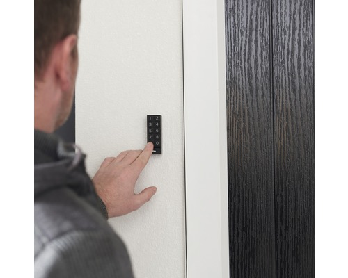 Person bedient ein elektronisches Türschloss mit Tastenfeld an einer Tür