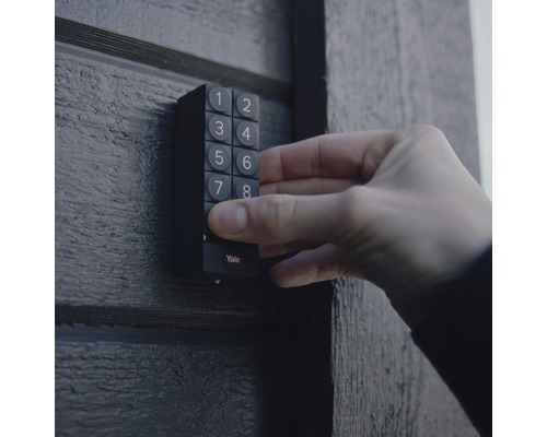 Eine Hand bedient ein Yale Zahlenschloss an einer Tür.