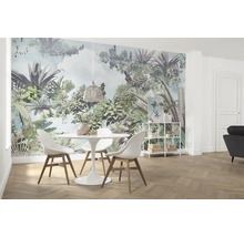 Salle à manger lumineuse avec papier peint jungle, table à manger et chaises.