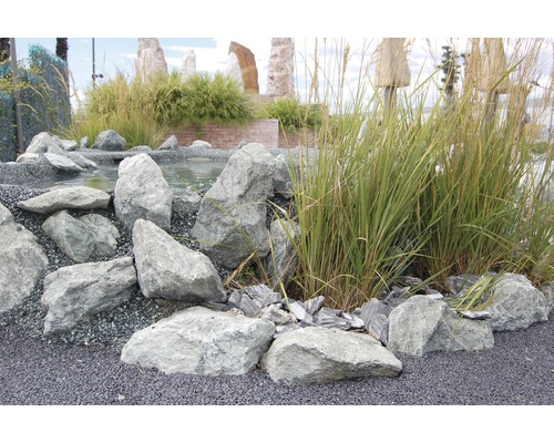 Gartengestaltung mit Steinen, Kies und Gräsern an einem Teich