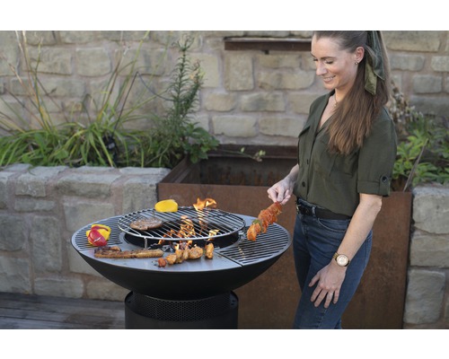 Frau grillt mit einer Feuerstelle im Garten.
