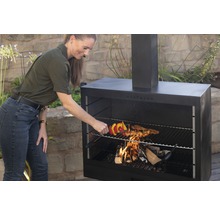 Frau grillt Fleischspieß auf einem Westmann Grillkamin im Freien