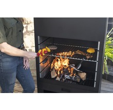 Frau grillt Gemüsespieße auf einem Holzkohlegrill.