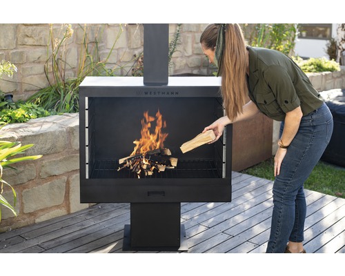 Frau legt Holz in einen Westmann Kaminofen im Außenbereich