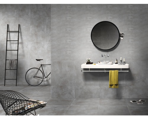 Modernes Badezimmer mit grauen Fliesen, rundem Spiegel und minimalistischen Möbeln.