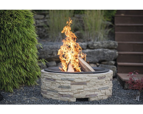 Feuerstelle aus Stein mit brennendem Holz im Garten