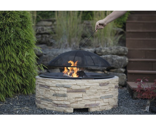 Feuerstelle mit Steineinfassung und Schutzgitter im Garten