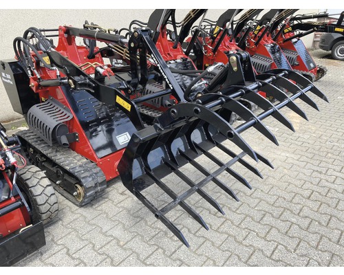 Plusieurs mini-chargeuses rouges PowerPac avec accessoires noirs sont disposées sur un sol pavé.