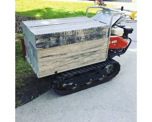 Kettendumper mit gefüllter Mulde für den Transport von Baumaterialien im Garten