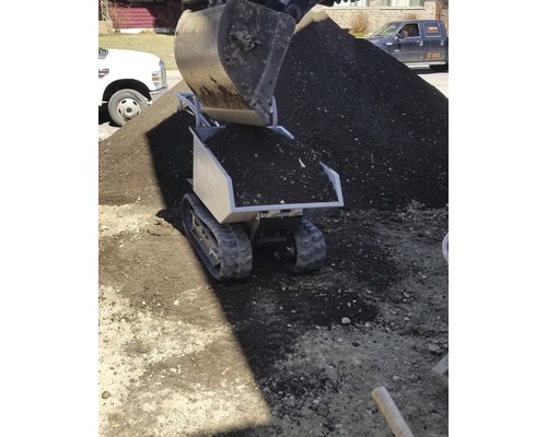 Mini-dumper à chenilles et terre rempli par une pelle mécanique