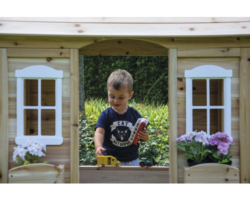 Garçon jouant dans une cabane en bois avec des véhicules jouets
