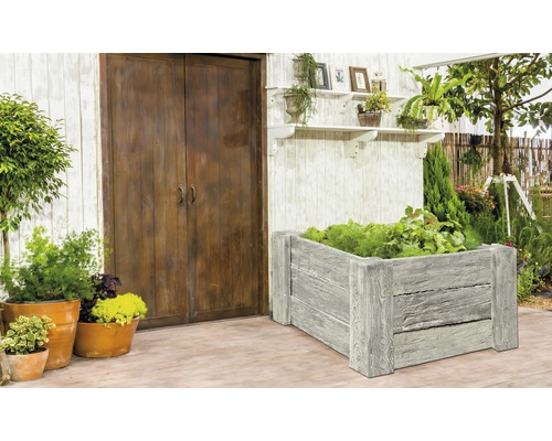 Scène avec parterre surélevé, plantes et décoration de jardin devant une porte en bois.