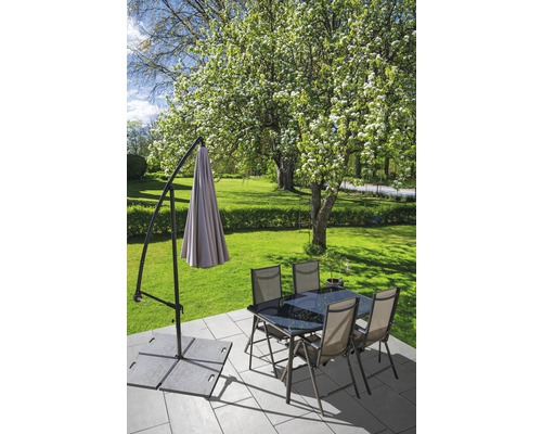 Szene im Freien mit Ampelschirm, Esstisch und Stühlen auf einer Terrasse.