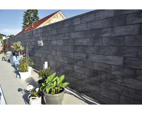 Garten mit grauer Steinmauer und Pflanzen in Töpfen
