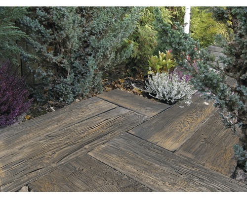 Gartenweg aus Holzpflastersteinen in Fischgrätmuster, umgeben von Pflanzen