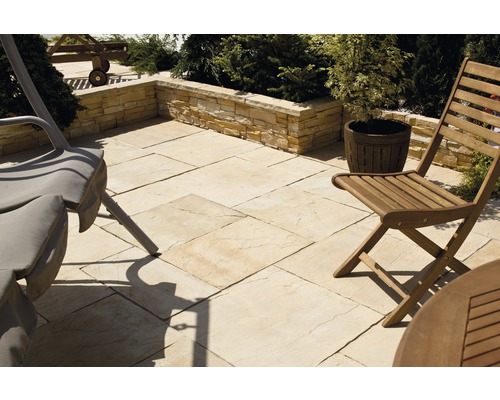 Gartenszene mit Terrassenplatten, Mauer und Gartenmöbeln