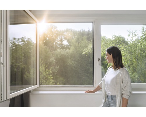 Geöffnetes Fenster in einem hellen Raum mit Blick auf eine Baumlandschaft