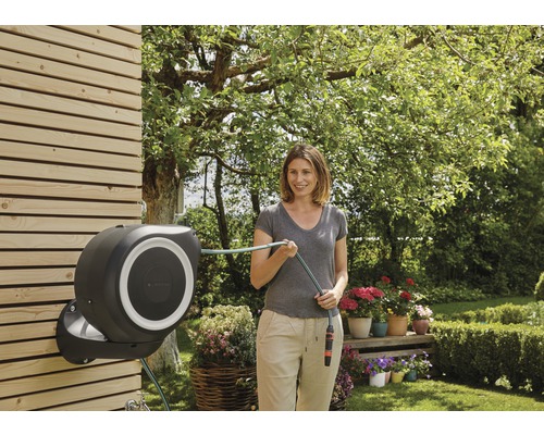Femme utilisant un dérouleur de tuyau automatique dans le jardin