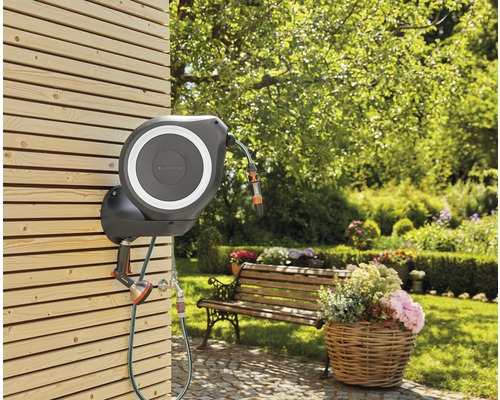 Scène de jardin avec enrouleur de tuyau Gardena sur un mur en bois