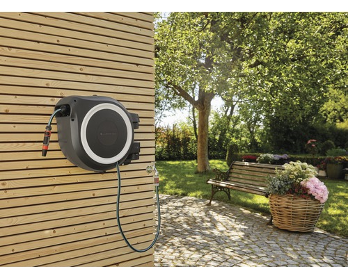 Gartenszene mit montierter Schlauchbox an einer Holzwand