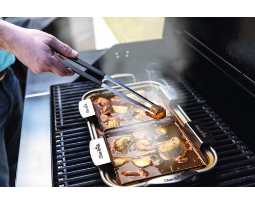 Plat à griller avec fruits de mer et légumes soulevé avec une pince à barbecue