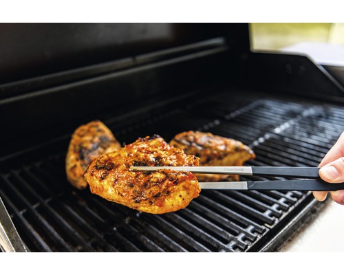 Pince de barbecue tenant du poulet sur la grille