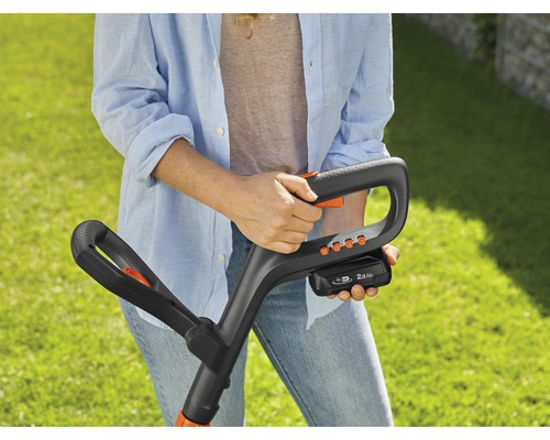 Femme tenant un coupe-bordures à batterie dans ses mains