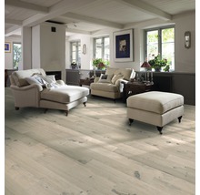 Wohnzimmer mit hellem Holzboden, Sesseln und Ottomane