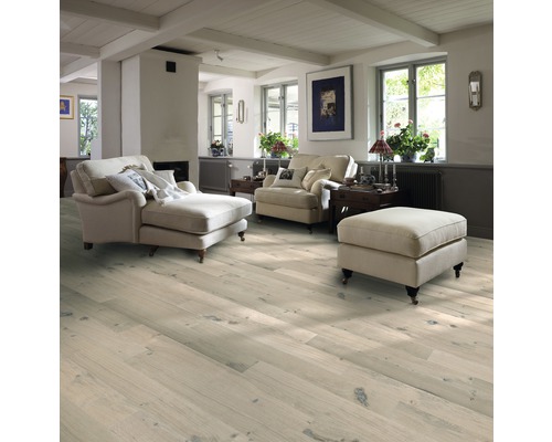 Wohnzimmer mit hellem Holzboden, Sesseln und Ottomane