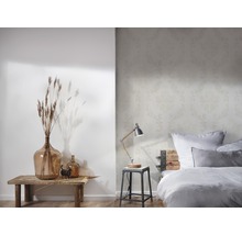Chambre claire avec papier peint à motifs floraux, lampe de chevet et décoration sur une table en bois
