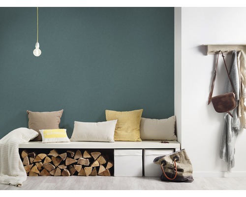 Wohnzimmer mit grüner Wand, Sitzbank, Kissen, Holzscheiten, Aufbewahrungsboxen und Garderobe