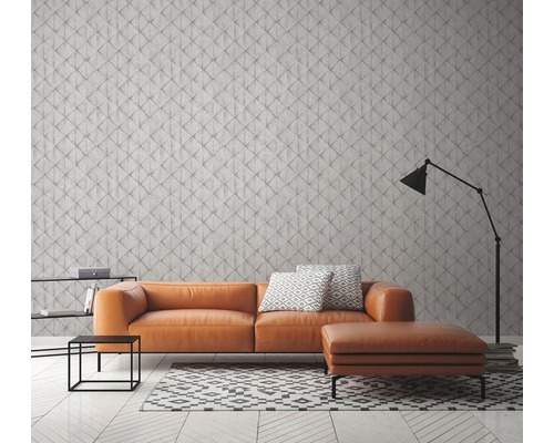 Wohnzimmer mit orangefarbenem Sofa, geometrischem Teppich und Stehlampe vor einer gemusterten Wand