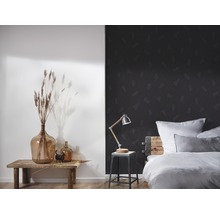 Chambre avec lit, lampe et décoration devant un mur avec papier peint géométrique