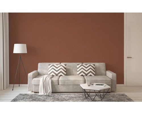 Wohnzimmer mit Couch, Kissen, Tisch und Stehlampe vor brauner Wand