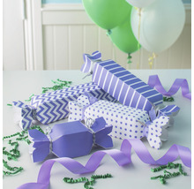 Une sélection de pétards de fête avec différents motifs et rubans sur une table avec des ballons