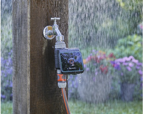 Gardena Wasserhahn mit Bewässerungssteuerung und angeschlossenem Gartenschlauch im Regen