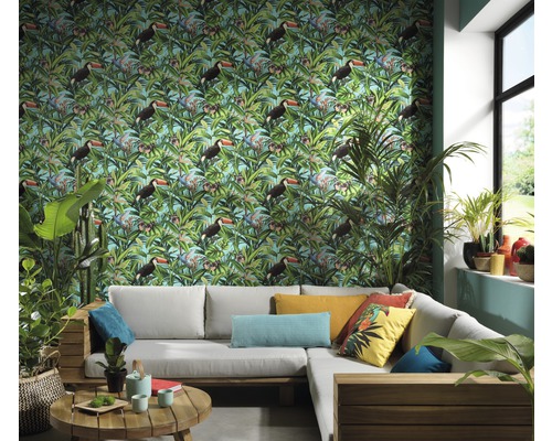 Wohnzimmer mit einer Wandtapete mit tropischem Tukanmuster, einer grauen Eckcouch und Zimmerpflanzen für ein helles und organisiertes Ambiente.