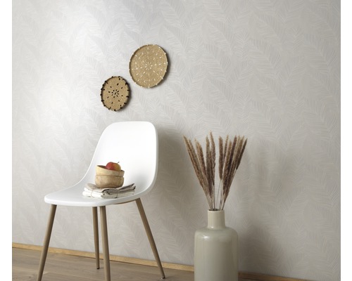 Dekoratives Zimmer mit gemusterter Tapete, weißem Stuhl, Vasen und Wanddekoration