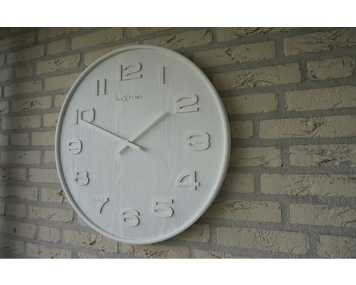 Nextime Logo Horloge murale ronde sur mur de briques