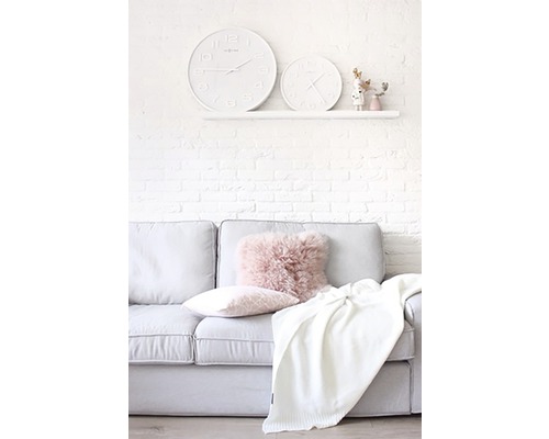 Salon avec canapé, coussins, couverture et deux horloges au mur