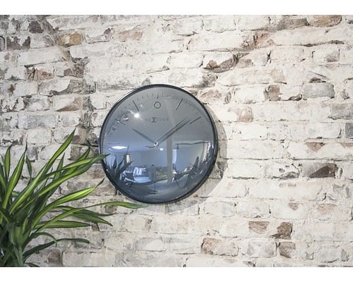 Nextime Wanduhr an einer Ziegelwand