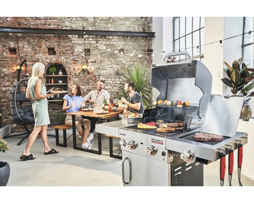 Scène d''extérieur avec un barbecue, une personne servant de la nourriture et un groupe de personnes assises à une table