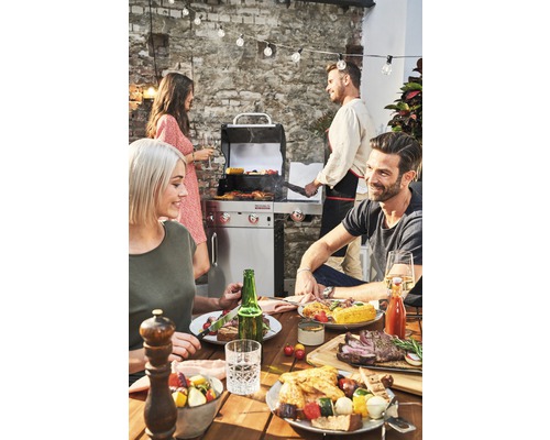 Scène de barbecue en extérieur avec table, barbecue et personnes faisant la fête