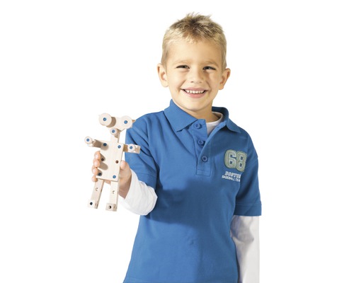 Un garçon tient un jouet de construction en bois.