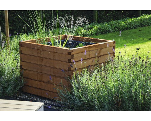 Quadratischer, hölzerner Teich im Garten mit Wassersprinkler