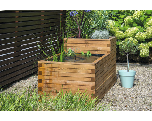 Jardinière surélevée en bois avec eau et plantes dans le jardin