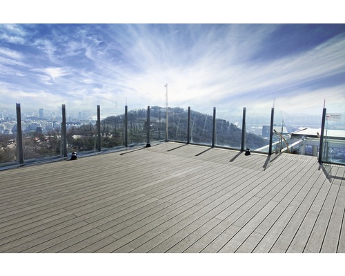 Terrasse avec planches en bois et garde-corps en verre donnant sur une ville