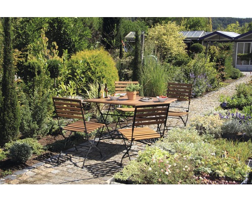 Gartenszene mit Holztisch und Stühlen im Freien umgeben von Pflanzen